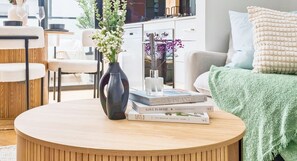 Ein runder Holztisch mit einer Vase, Büchern und einem Glas.