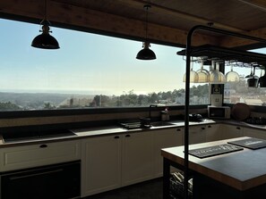 A kitchen with a view of the landscape, a sink, cabinets, and a countertop with appliances.
