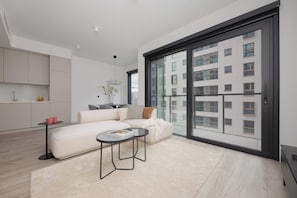 Ein modernes Wohnzimmer mit einer Couch, einem Couchtisch und einer großen Schiebetür, die auf einen Außenbalkon führt.