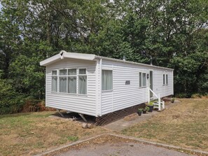 A single-story mobile home with a front porch, a small attached garage, and a covered outdoor area. - Plot 13A (Ruthin)