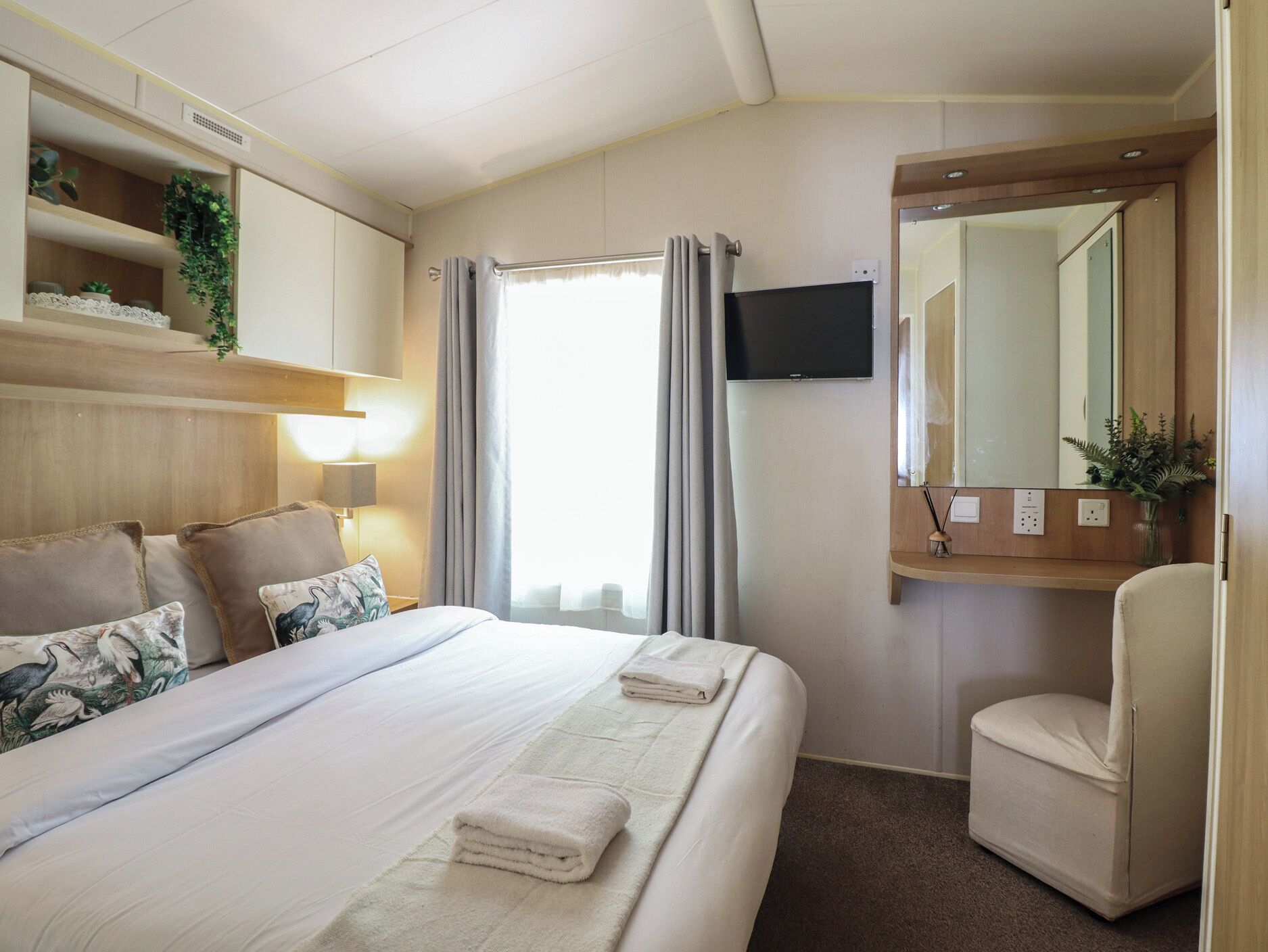 A hotel room with a bed, a chair, a TV, and a mirror.
