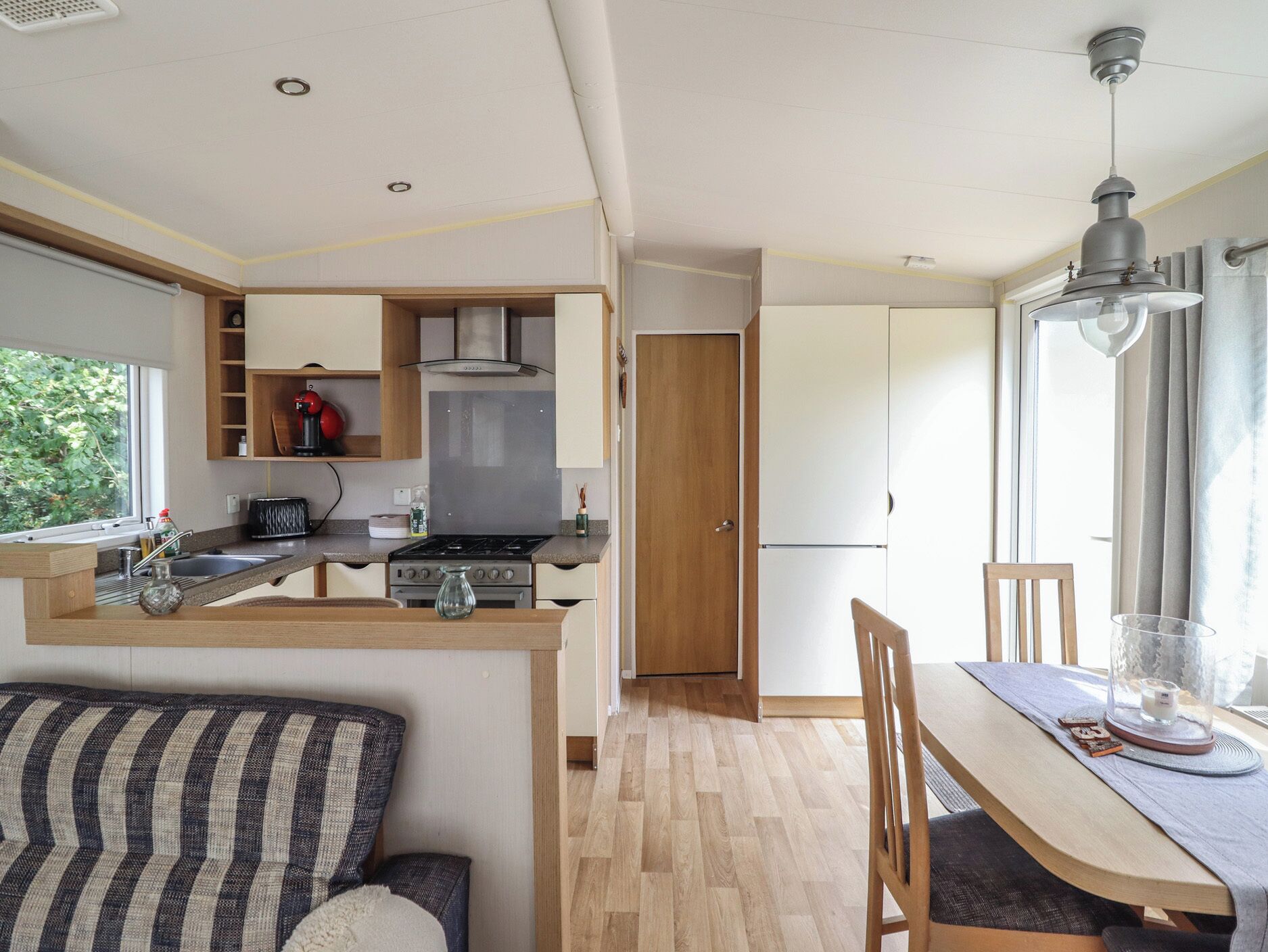 Cocina compacta con comedor, muebles de madera y ventana que proporciona luz natural.