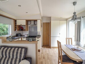 A compact kitchen with a dining area, wooden furniture, and a window providing natural light. - Plot 13A (Ruthin)