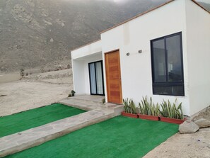 A modern house with a white exterior, a wooden door, and a large window.