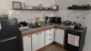 A kitchen with a refrigerator, stove, microwave, sink, and various kitchen items on the countertop.