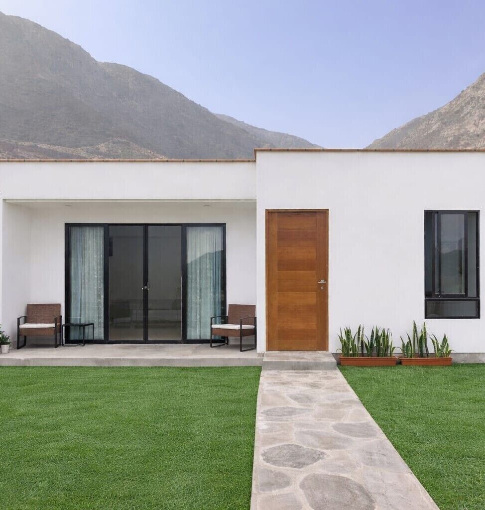 A modern building with a white facade, a wooden door, and a glass sliding door entrance.