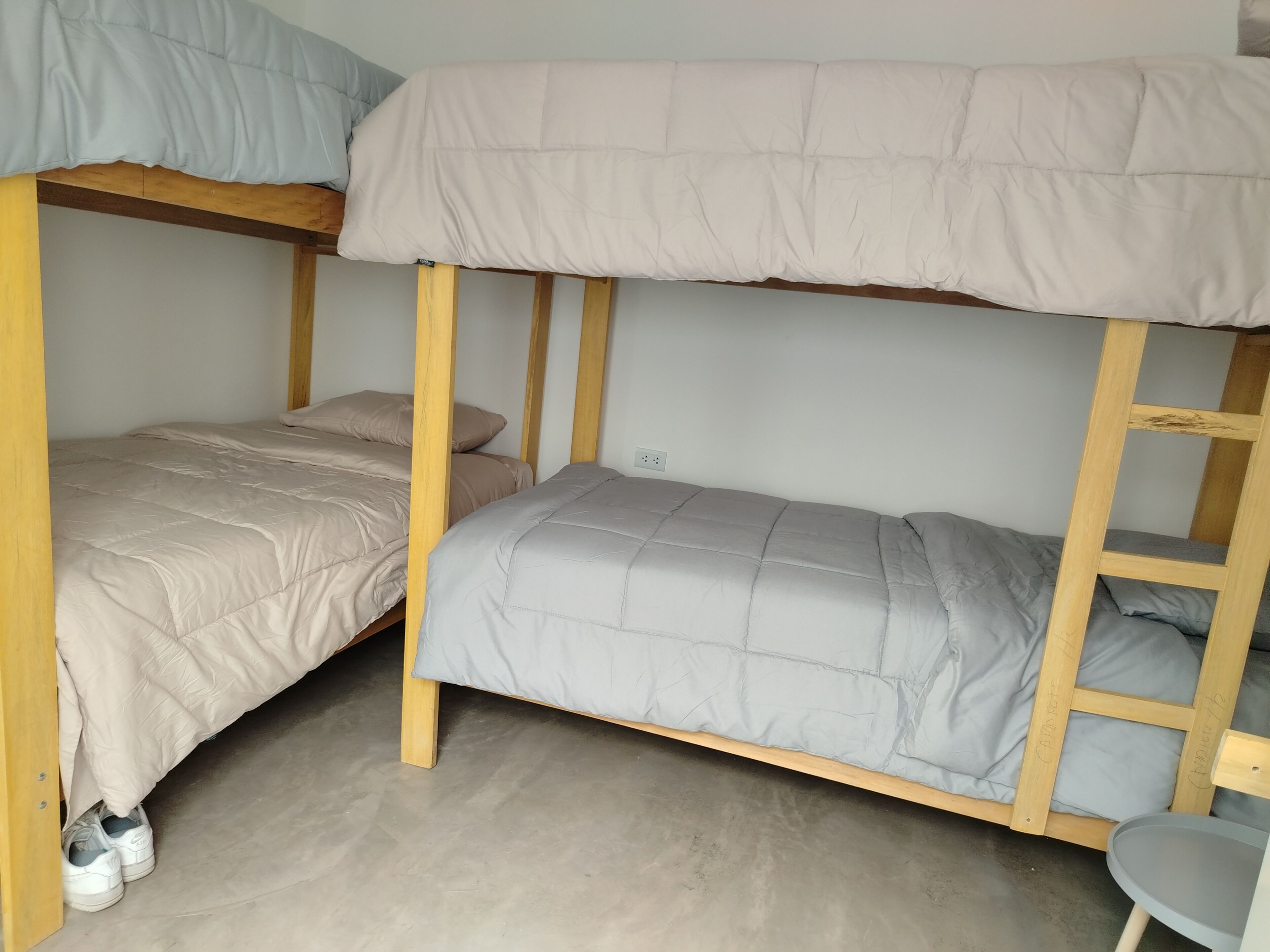 Ein Stockbett mit Holzbettgestell, einer grauen Matratze und einer beigen Matratze.