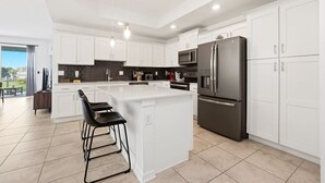Une cuisine moderne avec des meubles blancs, un îlot central et des appareils électroménagers en acier inoxydable.