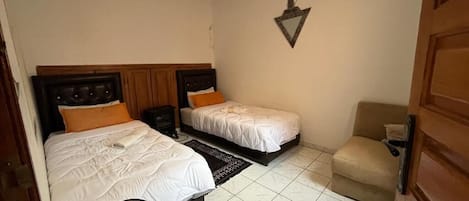 Un dormitorio con dos camas, una mesita de noche, una lámpara y un adorno en la pared.