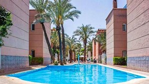 A swimming pool surrounded by buildings with a clear sky. - Riad Flouris in marrakech (Marrakech)
