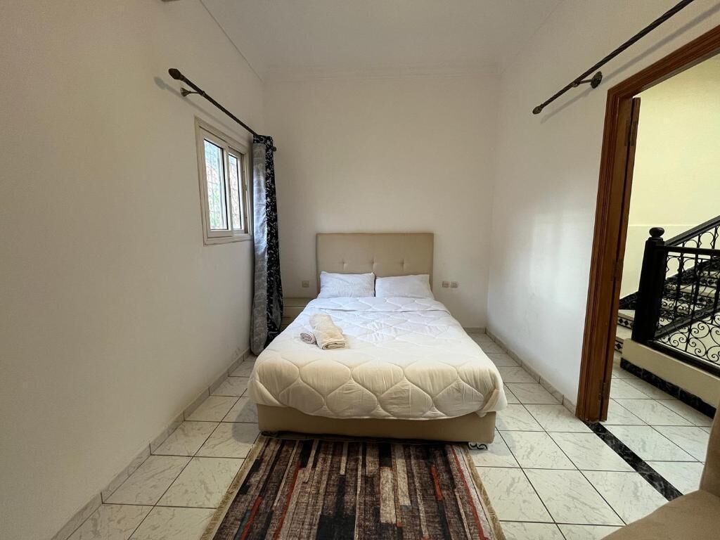 A bedroom with a bed, a window, a door, and a staircase.
