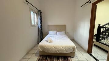 A bedroom with a bed, a window, a door, and a staircase.
