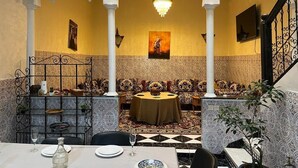 A dining area with a high ceiling, patterned walls, and a chandelier. - Riad Flouris in marrakech (Marrakech)