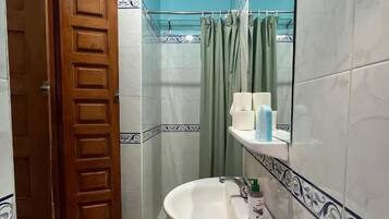 A bathroom with a sink, mirror, and shower curtain.