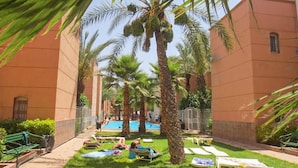 A courtyard with palm trees, a swimming pool, and lounge chairs. - Riad Flouris in marrakech (Marrakech)