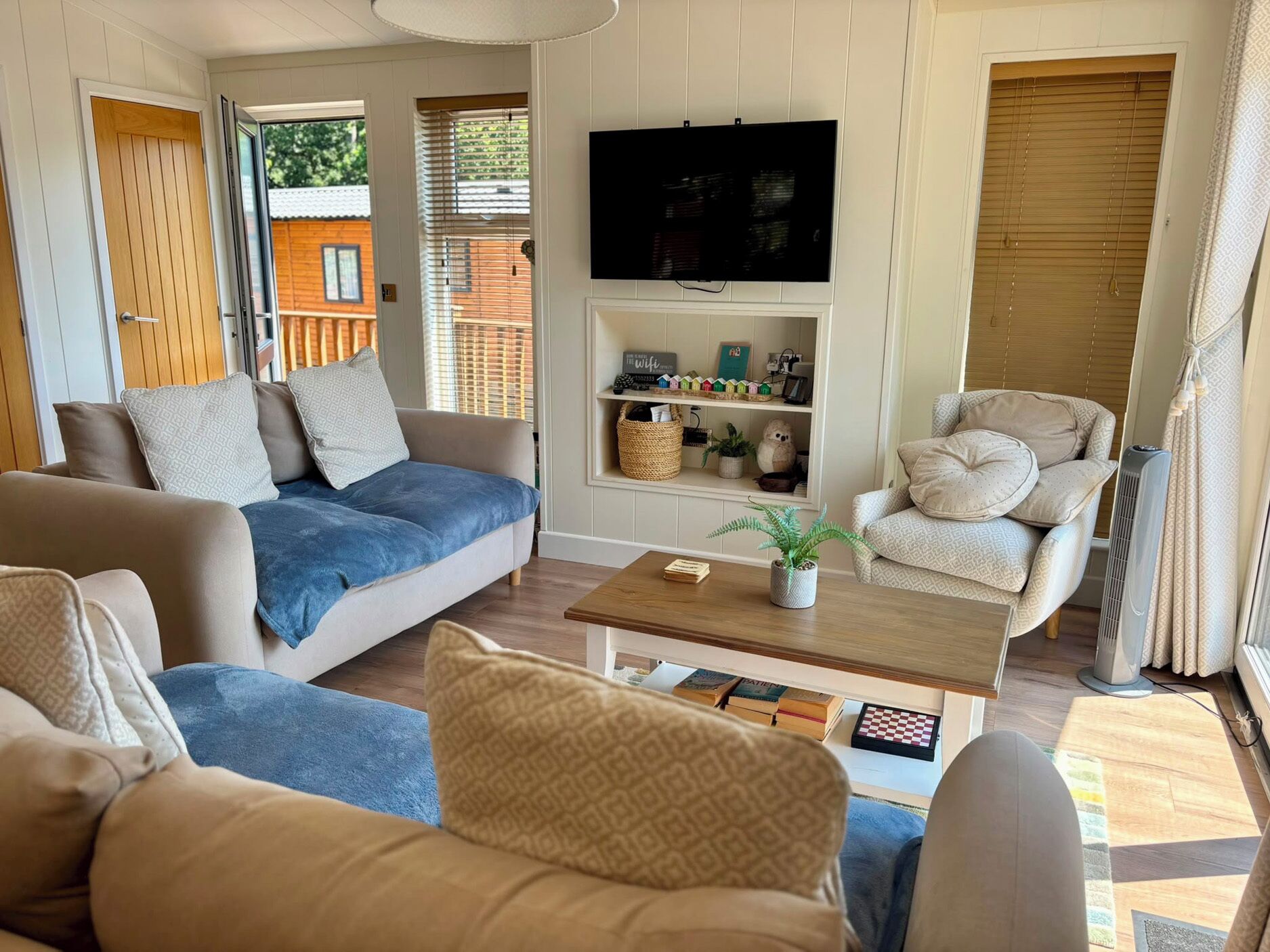 Ein Wohnzimmer mit einer Couch, Sesseln, einem Couchtisch und einem an der Wand befestigten Fernseher.