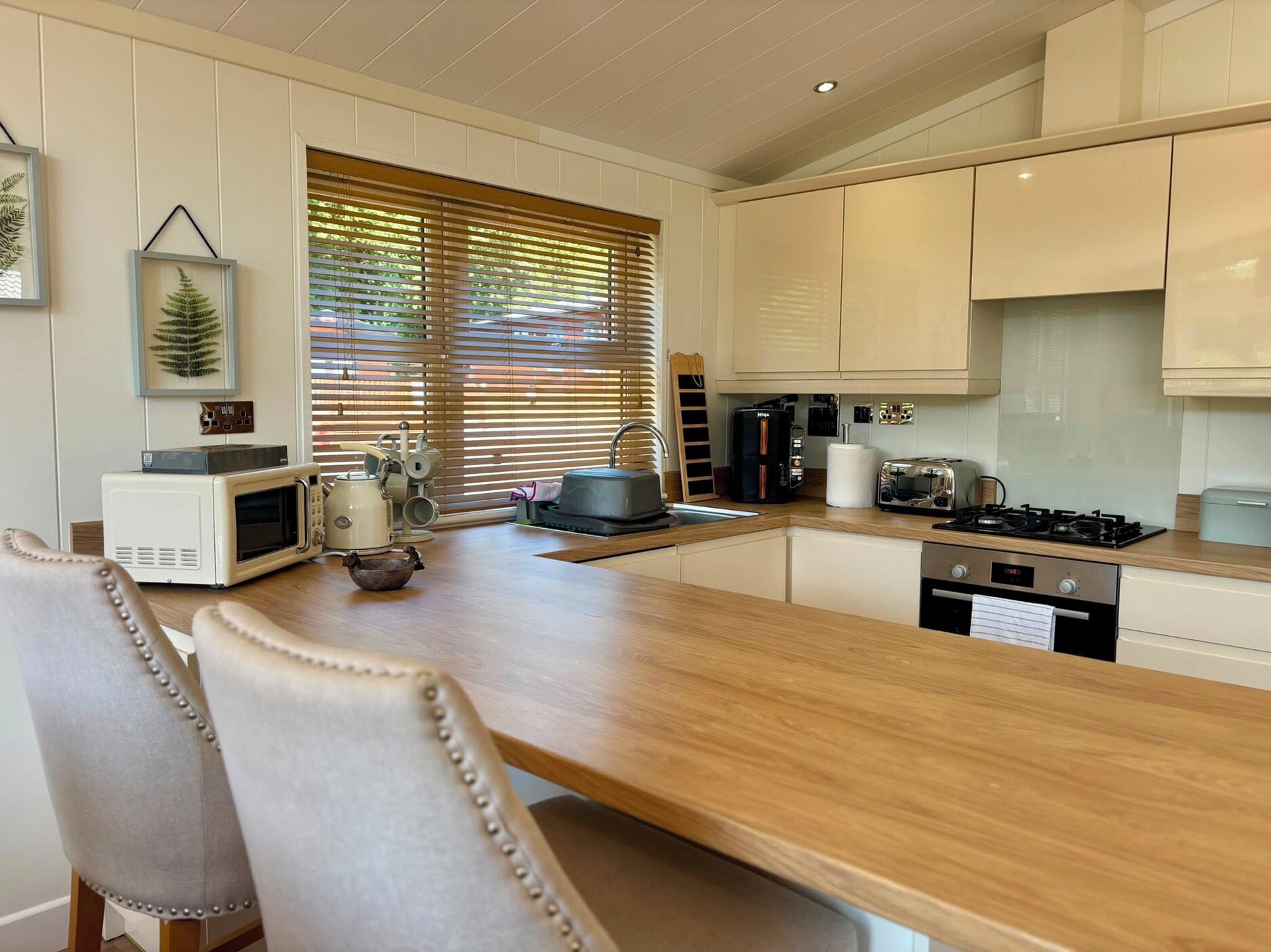 Una cocina moderna con armarios blancos, encimera de madera y un comedor con dos sillas.