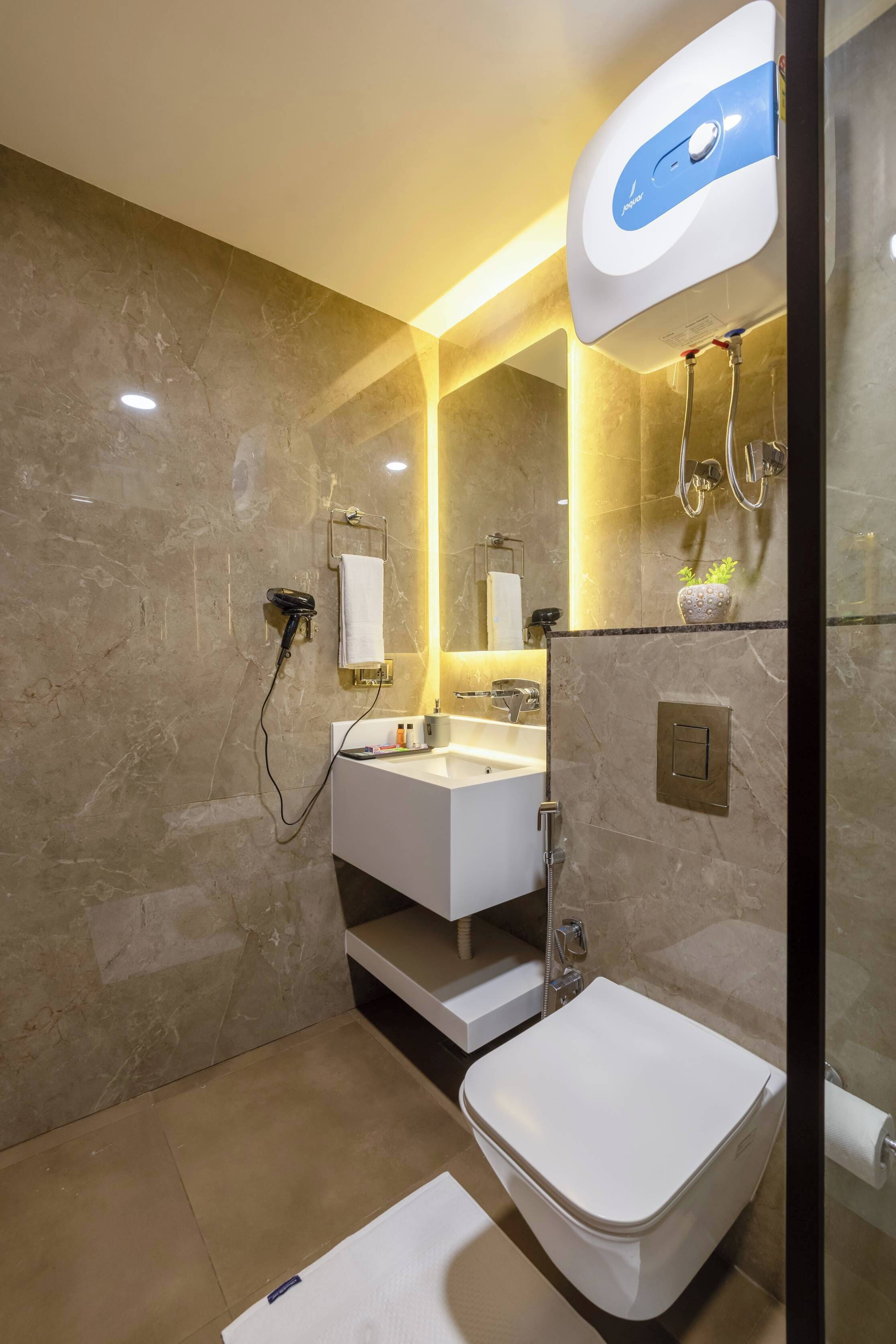 A modern bathroom with a marble wall, a white sink, a toilet, and a shower area.