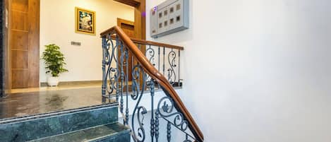A staircase with a wooden handrail and black metal balusters, leading to a landing with a wooden door and a framed picture on the wall.