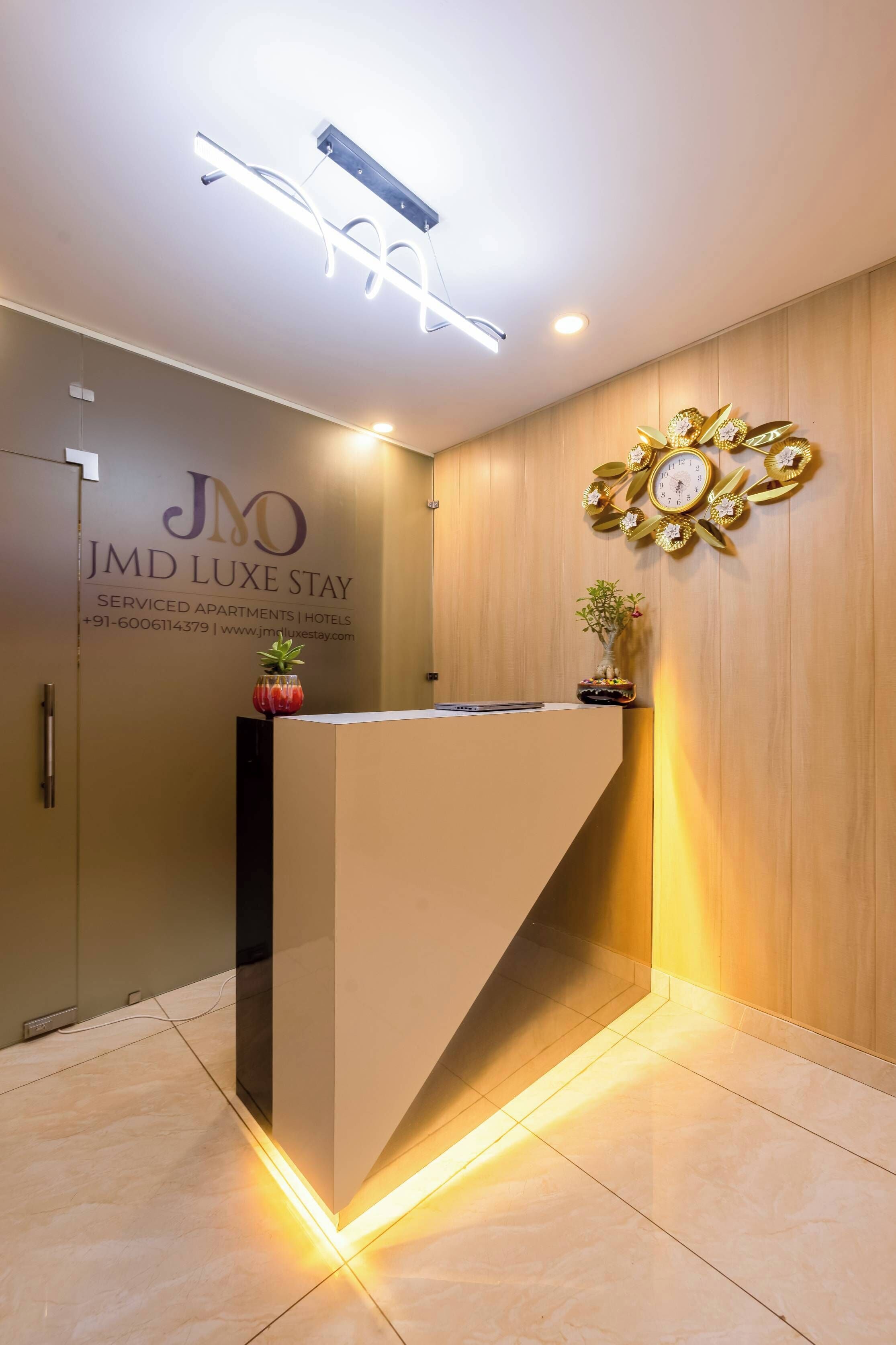 Una recepción con diseño moderno, un reloj de pared y un número de contacto para JMD Luxe Stay.