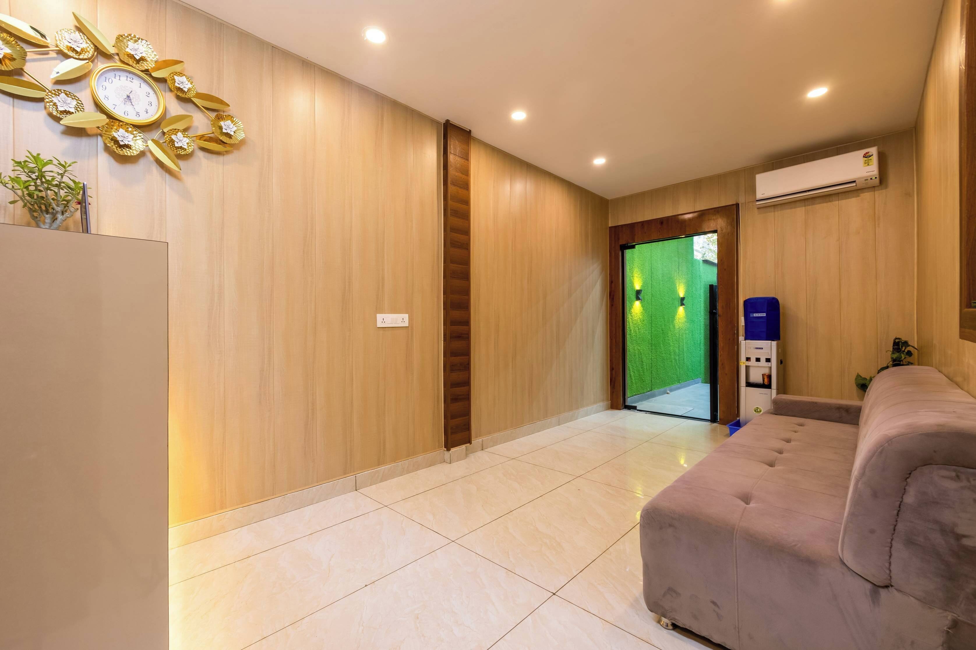 A hotel lobby with a reception desk, a clock, a sofa, and a green wall.