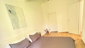 Ein Schlafzimmer mit einem großen Bett, einer Tür und einer Wandleuchte.