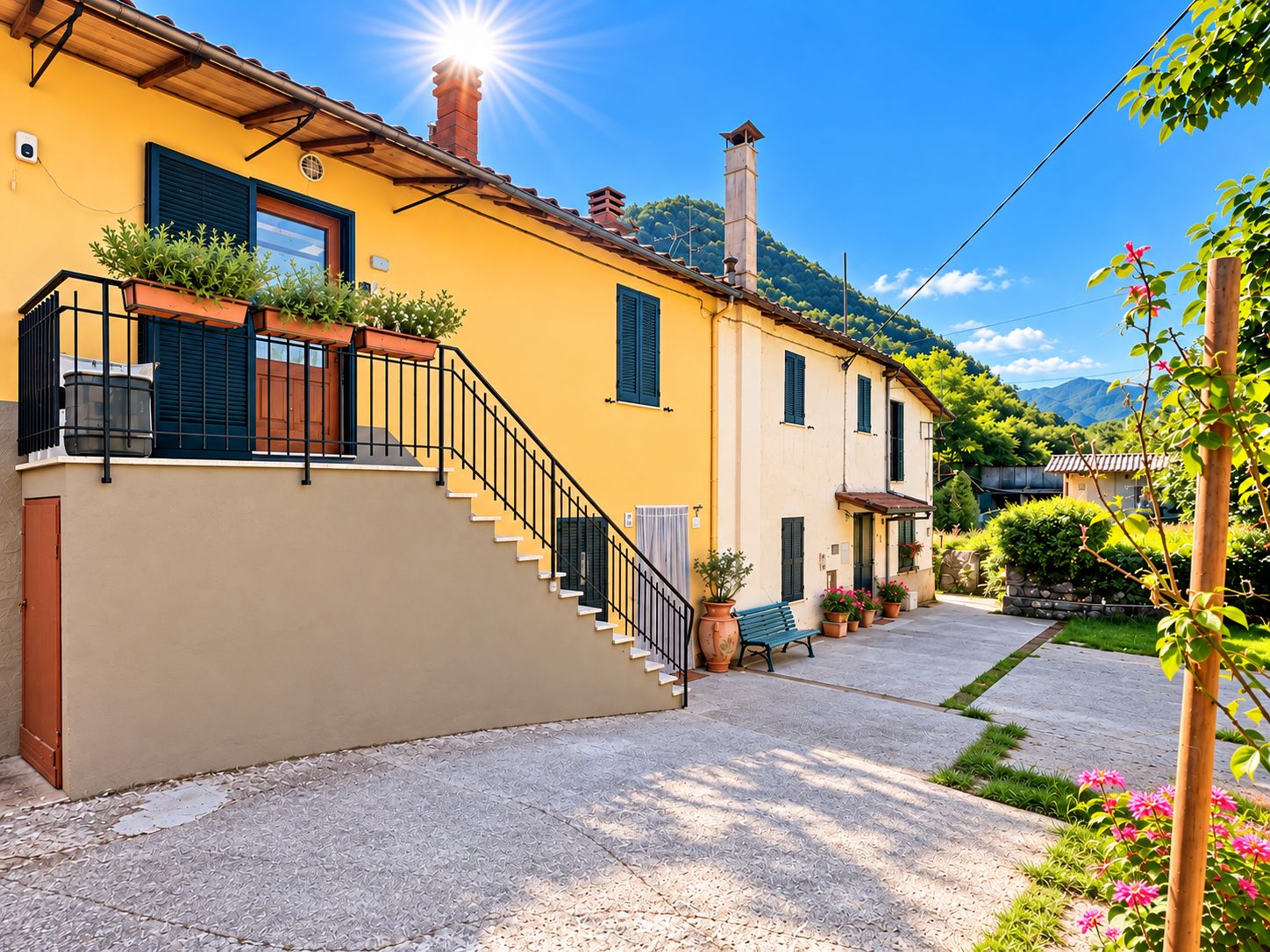 A yellow building with a staircase leading to a balcony, surrounded by greenery and a clear sky.