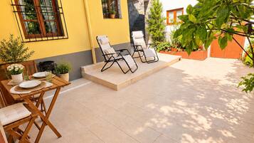 Ein gelbes Gebäude mit einer Terrasse, die Sitzgelegenheiten und Pflanzkübel bietet.