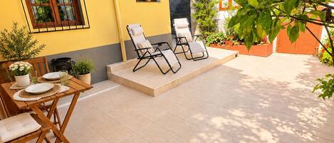 A yellow building with a patio area featuring outdoor seating and potted plants.