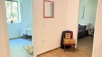 Ein Zimmer mit Holzboden, einem Spiegel an der Wand und einer Tür zu einem anderen Raum.
