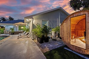 A modern house with a pool, lounge chairs, and a sauna.