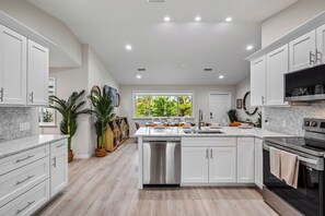 A modern kitchen with white cabinetry, a stainless steel dishwasher, and a black oven.