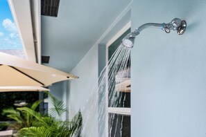 Un pommeau de douche fixé au mur, dont l’eau s’écoule.
