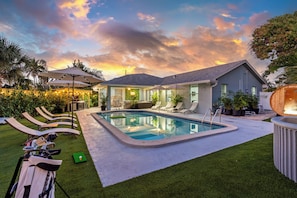 Une maison moderne dotée d’une piscine, d’un espace salon extérieur et d’une pelouse bien entretenue.