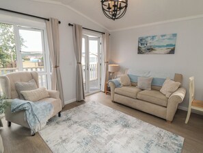 A living room with a sofa, armchair, and a large window with curtains. - Sea Glass Lodge (Saltburn-by-the-Sea)