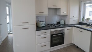 A modern kitchen with white cabinets, a gas stove, a built-in oven, and a window with a view. - Sea Glass Lodge (Saltburn-by-the-Sea)