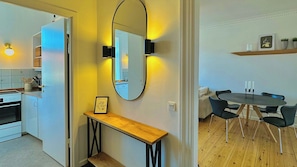 Eine moderne Küche mit Einbauofen, ein Essbereich mit rundem Tisch und Stühlen sowie ein großer Spiegel an der Wand.