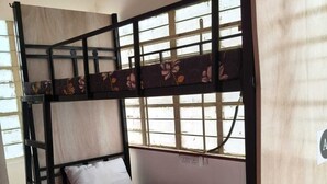 A bunk bed with a lower bunk and a single bed, a window with a floral pattern, and a wall-mounted sign with the letter 'A'. - Home away from home (Pune)