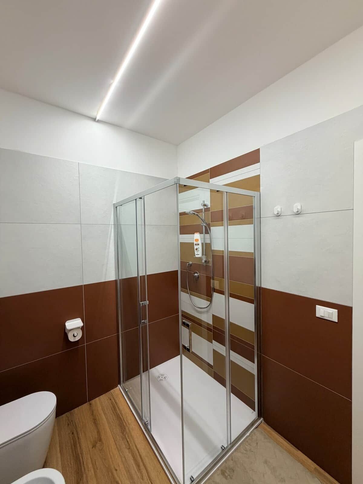 Un bagno moderno con doccia vetrata, un water e un lavandino.