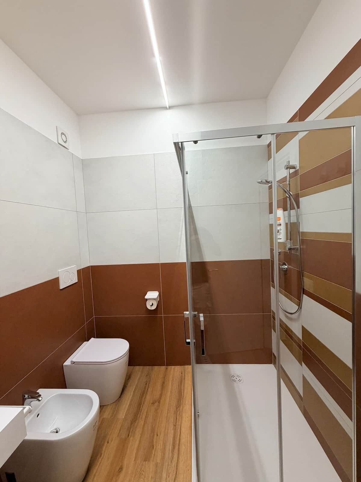 Ein modernes Badezimmer mit Duschkabine aus Glas, einem Bidet und einer Toilette.