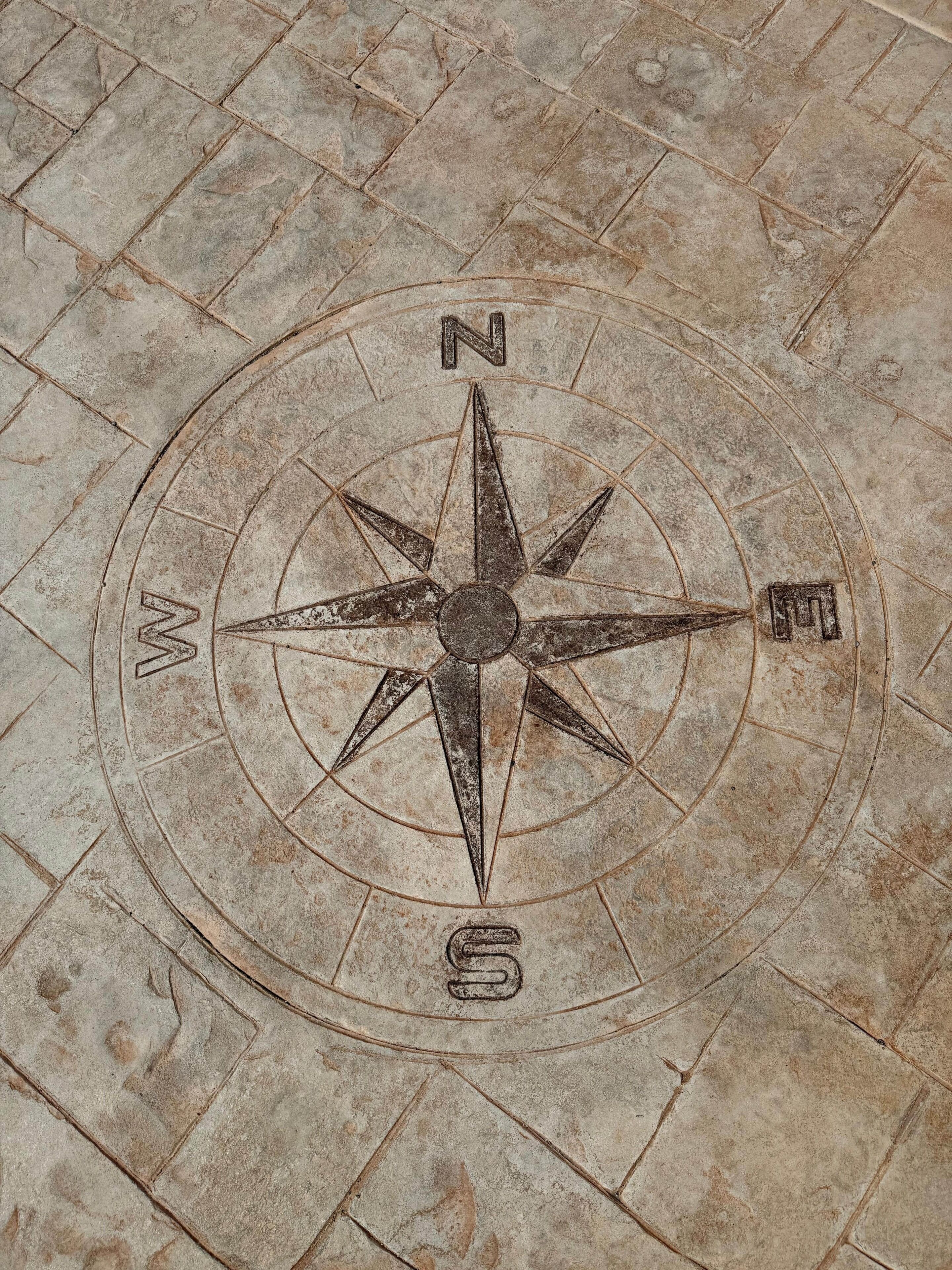 A compass rose embedded in a stone pavement.
