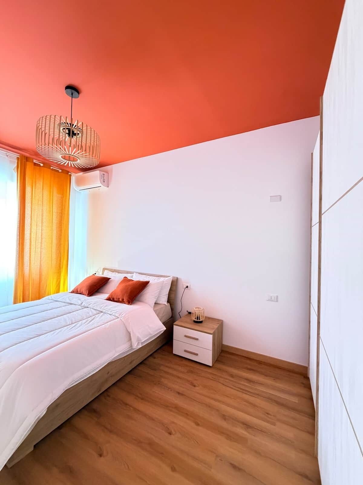 Een slaapkamer met een bed, nachtkastje en hanglamp.