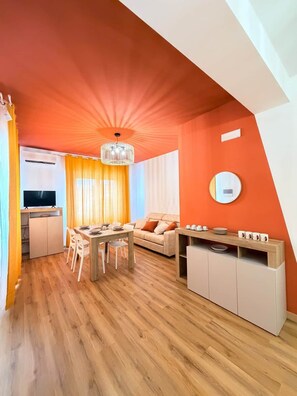 Een moderne woonruimte met een eethoek, een bank en een keuken met televisie en airconditioning.