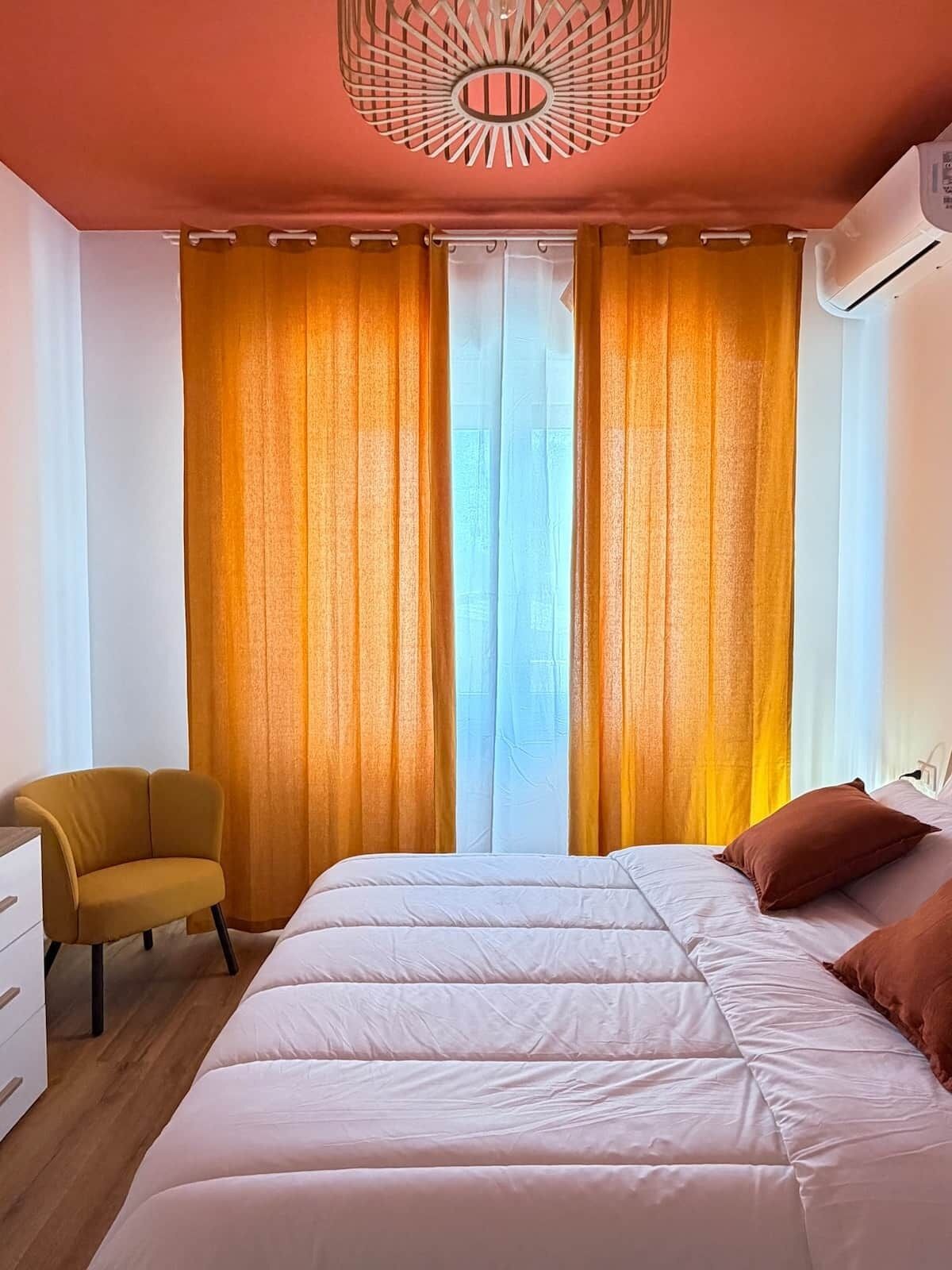 Une chambre à coucher avec un lit, une chaise et une fenêtre avec des rideaux.
