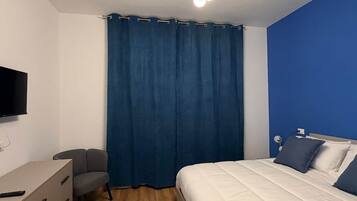 Una camera da letto moderna con un letto, una scrivania, una sedia, una televisione e una lampada a soffitto.