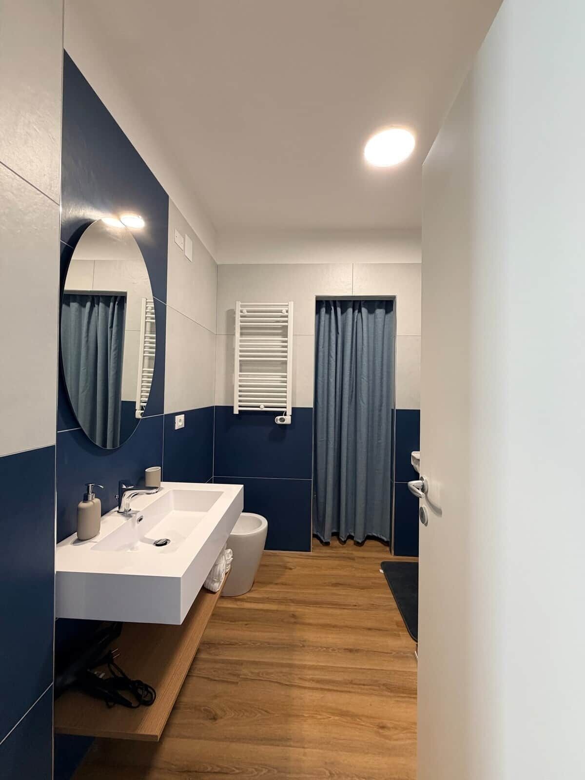 Un bagno moderno con lavandino bianco, specchio e portasciugamani.