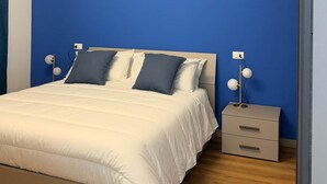 Une chambre à coucher avec un lit, des tables de chevet et un luminaire moderne.