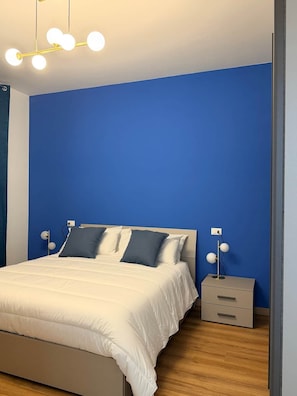 Un dormitorio con una cama, mesitas de noche y una lámpara moderna.