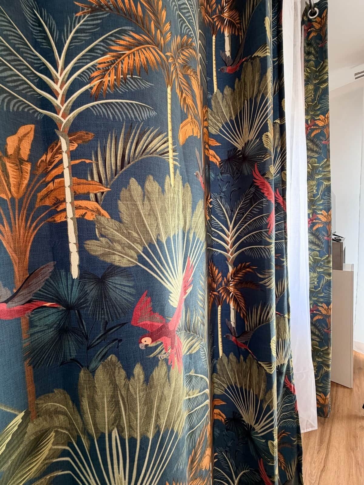Une pièce décorée d’un rideau orné d’un motif de feuilles tropicales.