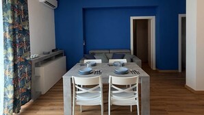 Un espace de salle à manger moderne avec un mur d’accent bleu, une table à manger pour quatre personnes et un luminaire suspendu au plafond.